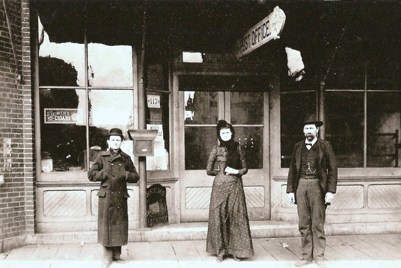 L-R: Lee Owings (Newsstand), Grace Vedder (Assistant Postmaster), Edward Bonapart Smith (Postmaster). Picture was taken about 1890 at 110 East Sherman Street, White Hall, IL.
