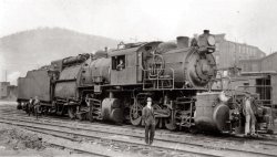 Erie 0-8-8-0 Camelback locomotive at Port Jervis, N.Y., in 1911. The camelback design was unique in that the engineer sat in the tiny cab alongside the boiler, while the fireman worked at the usual spot behind the boiler. One of the main disadvantages was the obvious communication problem between engineer and the rest of the train crew while the engine was in operation. The Erie camelback mallets didn't last long, but smaller camelback locomotives survived well into the 1950's on roads like the Jersey Central. View full size.
Photo&#039;s History?What might you know of the photo's history?  Interesting shot of a very rare locomotive.
Don Hall
Yreka, CA
Erie 0-8-8-0 CamelbackAt Port Jervis, N.Y., in 1911.I model trains in HO scale.  I have never seen anything like this engine.  I have seen 0-4-0, 0-6-0 and 0-8-0 camel engines, but never an articulated camel.  I have a 2-6-6-2 articulated and have seen the 4-8-8-4 UP engines, but not this one.  Anyone know where I could get more pictures of this engine?
Don Rowland - donhotrains@cinci.rr.com
[You could try contacting the person who posted this picture. First sign up for a user account, log in, click on his username, and then "contact." - Dave]
Erie 0-8-8-0 malletThe "Mother Hubbards," sometimes called "camelbacks", common on railroads in the Anthricite (hard coal) region of Pennsylvania.  IIRC there weren't many articulated locomotives built this way.  I believe this particular type of locomotive was typically used in "helper service," pushing coal trains over the mountains.
The design comes from the need for a very large firebox on locomotives burning hard coal.  Hard coal required a fairly thin fire to burn well, thus a large area was required to burn the amount of fuel required to generate enough steam.  The fact that they burned the lowest quality of coal available didn't help!
This particular locomotive is interesting in that it is a true compound; notice the size of the front low pressure cylinders compared to the high pressure cylinders on the rear engine.  This makes it a "true" Mallet.
It turned out that compounding didn't work as well as expected on railroad locomotives, and later articulated locomotives were built as "simple" engines.
I've never seen any of the larger Mother Hubbards in service, but I did see several of the smaller 0-6-0s and 0-4-0s in active service.
BTW &amp; FWIW - in the 70's we lived in McCloud for four years.  Beautiful country in that end of the state!
Erie 0-8-8-0- More photos (Link)There are a few more photos of these engines at:
http://www.rr-fallenflags.org/el/loco/erie-lmn.html
Erie Engine No. 2601 Derailed at Gulf SummitIn my wife's hometown paper (The Deposit Courier), the "Looking Back" section "100 Years Ago, 12 October 1910" says, "Erie engine No. 2,601, one of the largest engines in the world, was derailed at Gulf Summit Sunday night.  It was pulling a train of about eighty cars and was running along at a fairly good rate of speed when suddenly it left the track.  The big engine pounded along the rails for about 500 yards, cutting off the ends of the ties and tearing up the roadbed for a considerable distance.  The Susquehanna wrecking crew was called and repaired the damage."
Only oneThere was only one of this type of locomotive ever built, and it was used for only one thing. Hump work.  Basically this engine spent its whole life pushing long trains up the hump of a yard where they would be gravity sorted.  The idea behind the placement of the cab was more for visibility than anything.  As for communication, the engineer and fireman used their own whistles to communicate between themselves. The engineer used the train whistle, the fireman had a lighter, lower whistle he used.
There were three of theseThere were three of these used for pusher service, not hump service.  Only the ERIE had articulated camelbacks, no other road had them. They were all rebuilt later with their cabs at the back.
There were alot of camelbacks in the east and even some western roads had them: Santa Fe, Canadian Pacific, MKT, Chicago &amp; Indiana Coalm, C&amp;IE, to name a few.
There are more pictures all over the Internet, even a color painting.
An HO scale model just sold on Ebay for over $3000.00!
(ShorpyBlog, Member Gallery, Railroads)