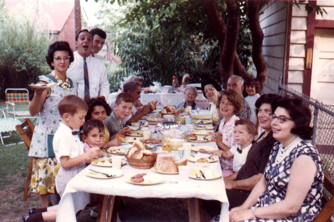This is one of our frequent backyard get togethers at my Aunt's home in Secaucus, NJ circa 1963. I'm the joker in the gray shirt. My Dad is behind me wearing a tie and my Mom is second from the right with the pearls.

My brothers are the little guys with bow ties and the rest of the kids are cousins. Except the lovely blonde girl directly across from me, a friend of my cousins, who I had a huge crush on for years. My grandparents are seated to my left and my great-grandmother is at the far end of the table. 

The photo was likely taken by my Uncle Gerard who always had a camera ready. His wife, my wonderful Aunt Greta, is the hostess holding the plate. 