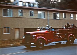 Firemen and volunteers cling to the back of the Larkspur Fire Department's 1946 American-LaFrance engine as it roars down Magnolia Ave. on the way to a call one late afternoon in 1963. These days we're used to seeing firemen suited up like they were about to take a moon walk; check out the casual attire here. Only one guy even has his fireman's hat on; two of the volunteers are sporting baseball caps. Everybody else is in shirtsleeves, even the full-time guy at the wheel (although it's his official blue uniform shirt). That's our house at the very top of the frame.

The fire department had been a governmental entity only 6 years. Up until 1957, it was privately operated by the volunteers, completely funded by dances held at The Rose Bowl, an outdoor dance floor under the redwoods that featured name bands and drew crowds from all over the Bay Area each Saturday during the summer months. My Kodachrome slide.