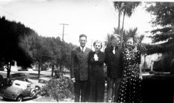 Another from my grandmother's photo album, no names on the back of the photo, but the gal on the right looks like my grandmother. I'm not sure who the others are, but I know the guy with his arm around her is not grandpa. This was likely taken around the time she graduated Hollywood High School in 1933. View full size.
Dressed for the roadsterWhoever that guy with your maybe-grandma is, he's one sharp dude. I'm going to have to assume that's his snappy roadster down at the curb. As for the when, the sedan on the other side of the street is a body style you didn't see until the 1935-6 model year for most cars.
(ShorpyBlog, Member Gallery)