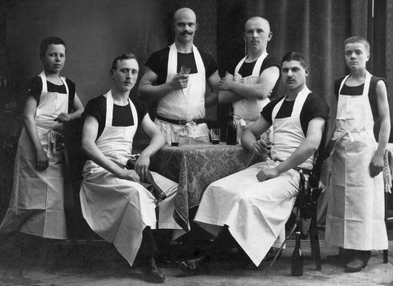 This image shows a German Master Butcher (center with mustache) with his companions. Left and right outside are the two apprentices. The companions have their personal tools on a belt. The photograph was taken in 1917 in Recklinghausen, Germany. View full size.
