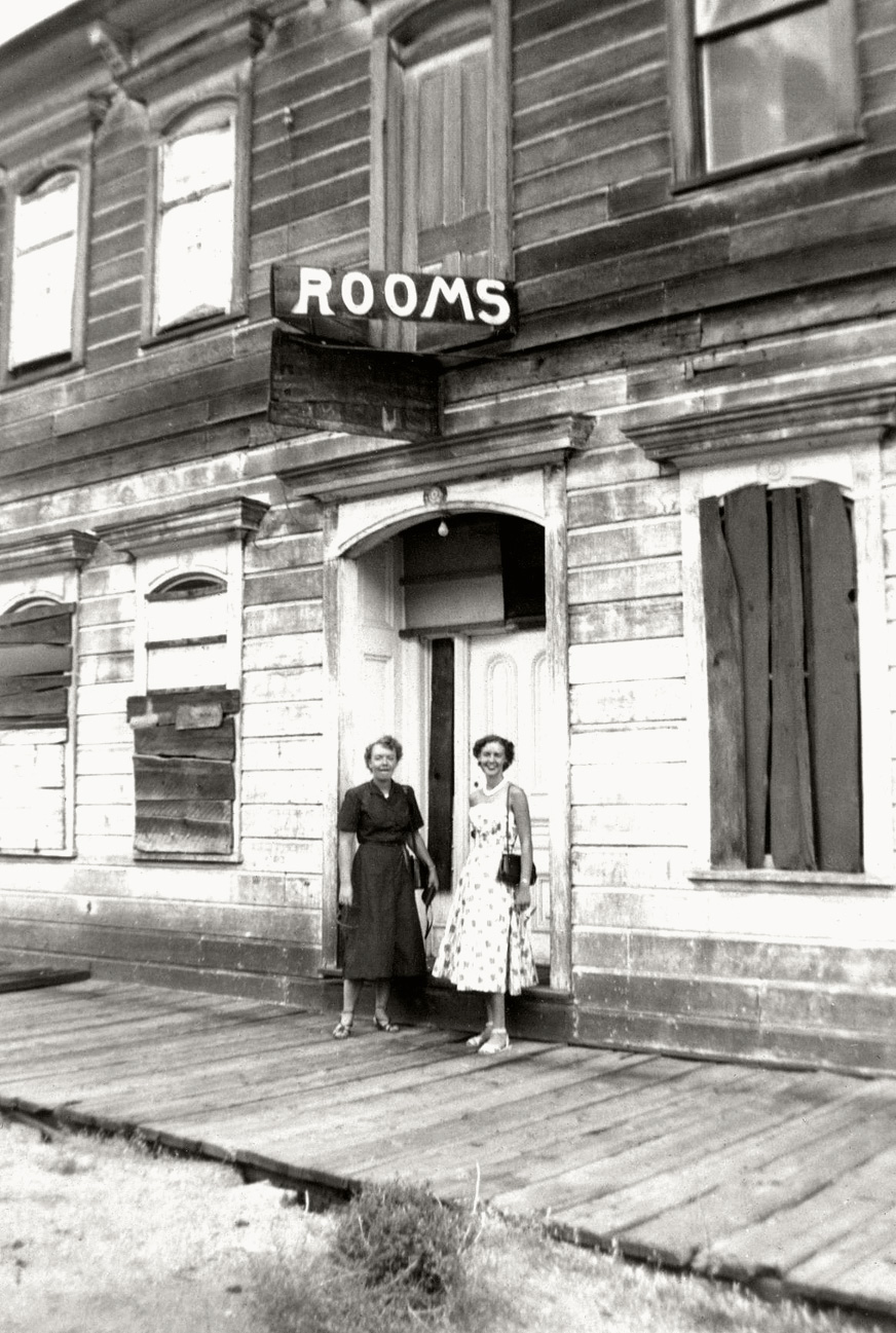 One of the same women who previously was seen posing in slacks and pedal pusher shorts, with a car and her sister, puts on a dress to pose with her mother in front of a California ghost town motel. From a collection of photos I found in a Simi Valley, California antique store. View full size.
