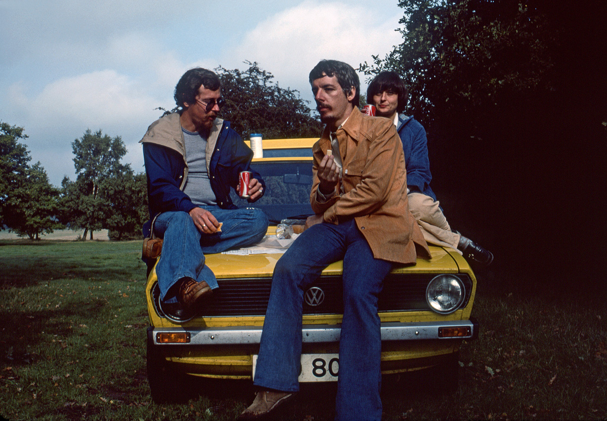 October 1976, somewhere in England. Holding a piece of good English cheese, I wait for the self-timer to snap, sitting with my friends on the bonnet of our for-hire Volkswagen Golf. Kodachrome slide via Konica Autoreflex T. View full size.