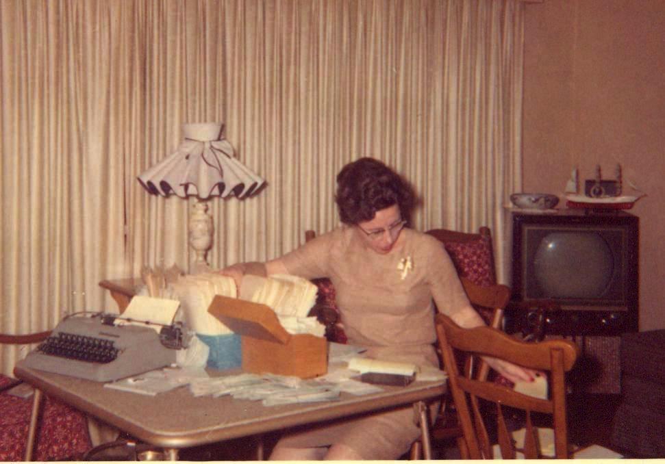 My mother in 1961, caught unawares by me as she worked on a tax filing. She's a bit dressed up because she just returned from a lunch hour rush at the steakhouse she and my dad owned, where she acted as hostess. My dad was in the bedroom, recovering from a severe heart attack (he did, and outlived three salt-free cardiologists). Mom said she didn't have time to even draw a breath in those years. That's our 1953 b&w Philco in the corner, and yes, the lampshade is scary. We thought it was beautiful then. View full size.