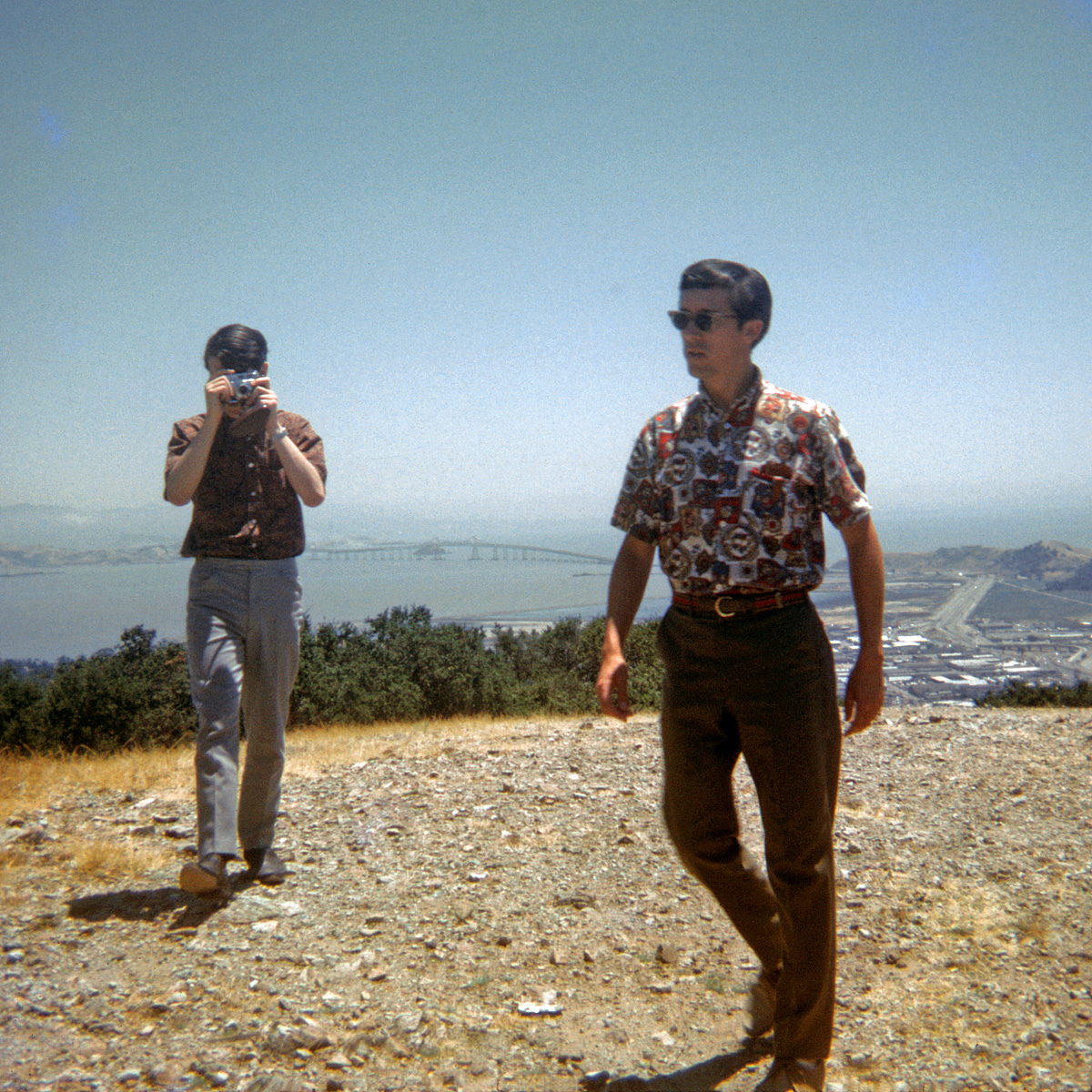A rare photo of me actually wielding a camera, in this case my Retinette, in 1967 atop a hill overlooking San Rafael, Calif., with the Richmond-San Rafael Bridge in the background. I'm not really aiming at my brother here, but at my friend while he was taking this 126 Kodachrome slide. I wasn't quick enough, and didn't get the shot. View full size.