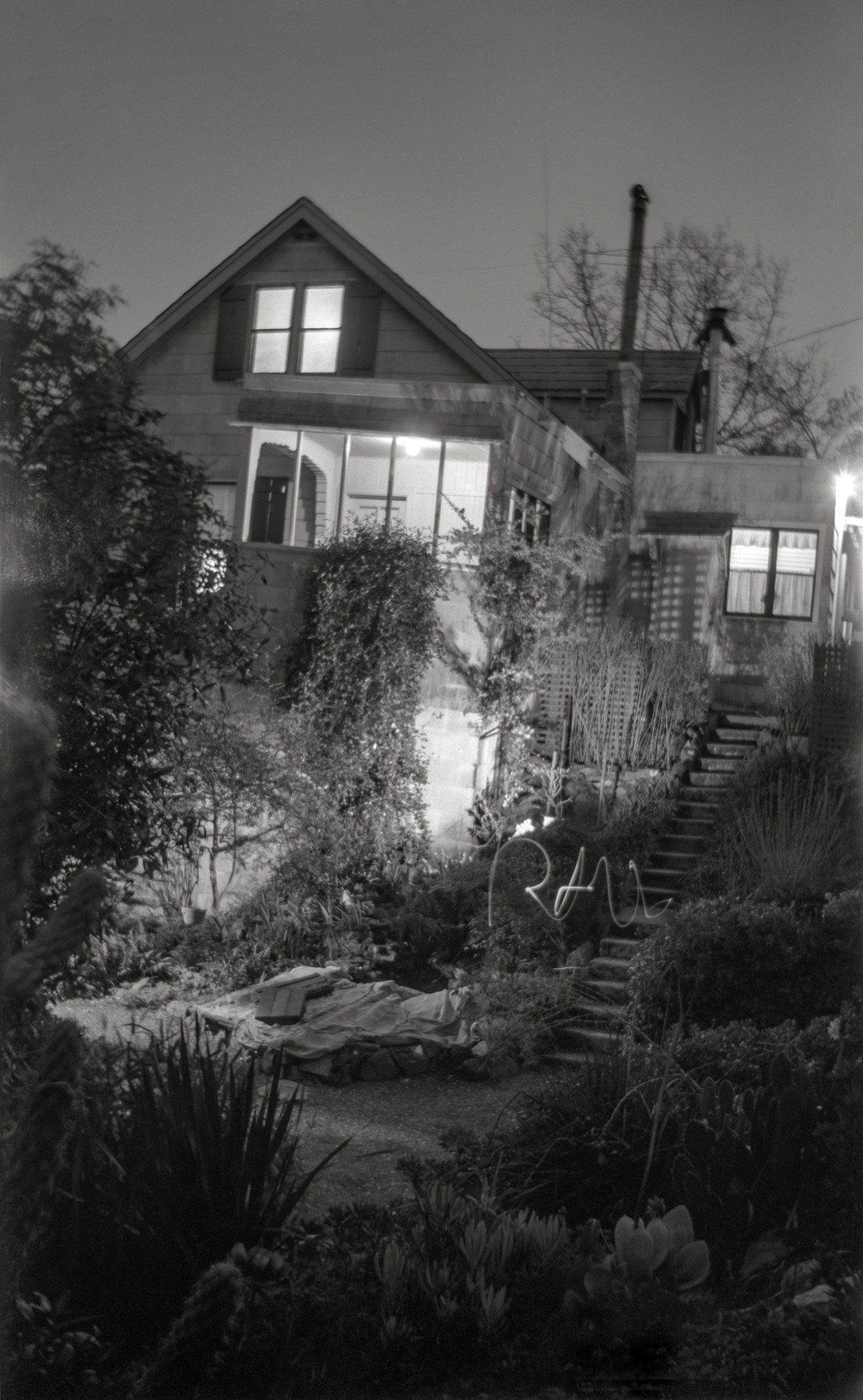 Shorpy being the Historic American Photo Archive, and me being American and at this point in my life historic, I present from my archive a nighttime photo experiment I performed in winter 1962 while a teenage camera geek. This is how I made this time-exposure of our Larkspur, California house: I turned on all the lights in the front-facing rooms, also those on the porches and front walk, and added one more (my desk lamp) below the front porch. I set up the camera (an old c. 1920 folding job) in the cactus garden, opened the shutter, ran down to the bottom of that stairway and wrote out my name with a little flashlight, then ran back up and closed the shutter. Voilà! I used that old camera, a Kodak Folding Autographic Brownie 2A, because it was the only one around the house then that could take time exposures. No tripod receptacle, so I had to balance it on something or other. (I know it's winter because of the burlap sacks covering the lantana for frost protection. Oh, and before you ask, no, we're not related to the Addams family.) Scanned from the original "116" 2½ x 4¼ negative, slightly cropped at top. View full size.