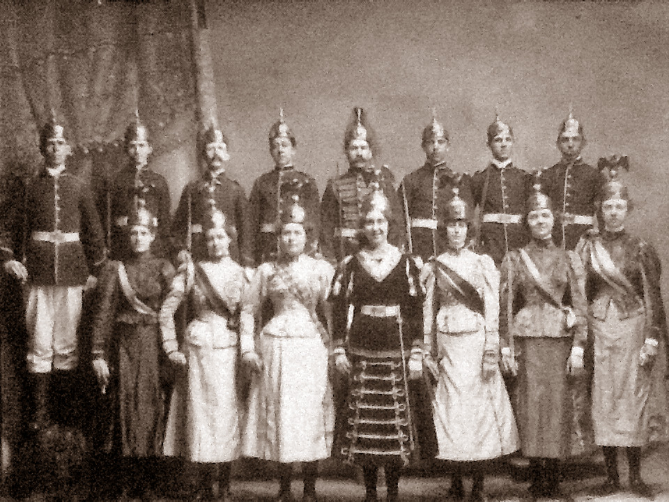Knights and maybe sisters of Pythias taken in Maine. My great grandpa was a young man (third from the left). Note the waist sizes of the women.  Can anyone explain the helmet on the head of the woman on the right in the first row?