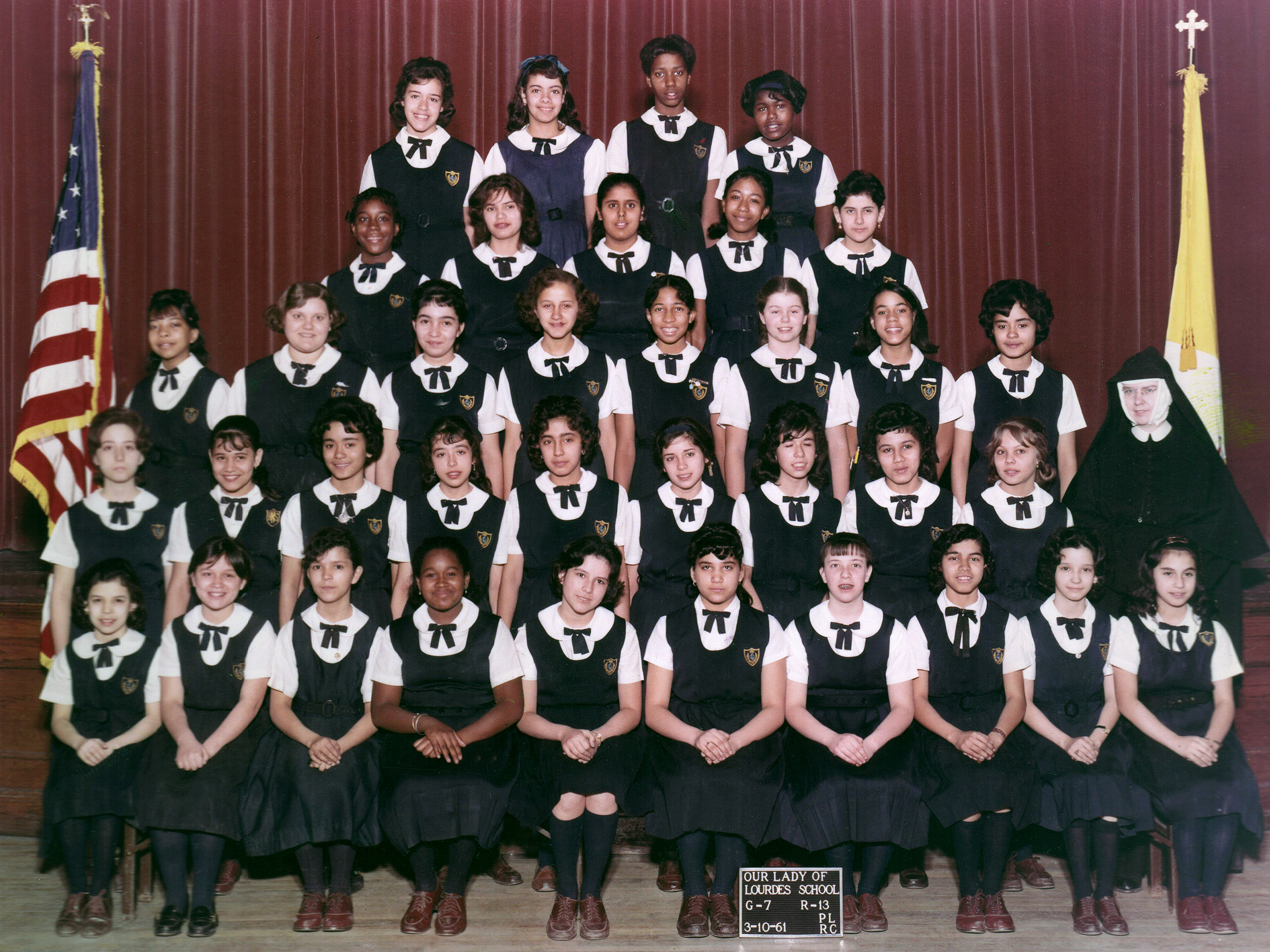 7th Grade Class at Our Lady of Lourdes School, 1961. I am in the back row at the right. View full size.

I had 35 girls as classmates; from the 5th to 8th grades the girls and boys were separated into same-sex classes, as it was believed at the time to be less of a distraction for students, so their focus would solely on getting an education. Still had a diverse group of students in March, 1961. I believe we would all pass our tests and be promoted to the 8th grade together.

It was in the 7th grade that I realized what the coveted position of being one of few teacher's pets entailed.  Being an only child, I felt lucky to have a first cousin attending the same school in a grade ahead of me to act as the big brother I didn't have, so when I discussed my new class position with him he just laughed at first and then schooled me on the reality of how the other students would soon treat me differently. Frankly, I didn't believe him, but a week later I noticed the change in attitudes and I also noticed that whenever the teacher was away from the classroom I was asked to monitor everyone's behavior and report any activity to her with names and what that person did or said: a rat fink, oh no. I definitely did not want to have that label because at lunchtime I wouldn't have anyone to jump rope with, and that was my favorite activity during that time period. I would be stunned, and outcast!!!

Did know that I was also being monitored and reported on as well and before long, I no longer had my desk right next to the teacher's, and in fact I was closer to the back of the room, not that far away from the ones who the teacher had said didn't want to learn anything.  I noticed my friendships were never the same, as I learned a lesson for myself from that brief experience: enjoy the company of others but not to depend on having it when you may need it the most, and self-reliance; stand alone and stand strong, if need be.