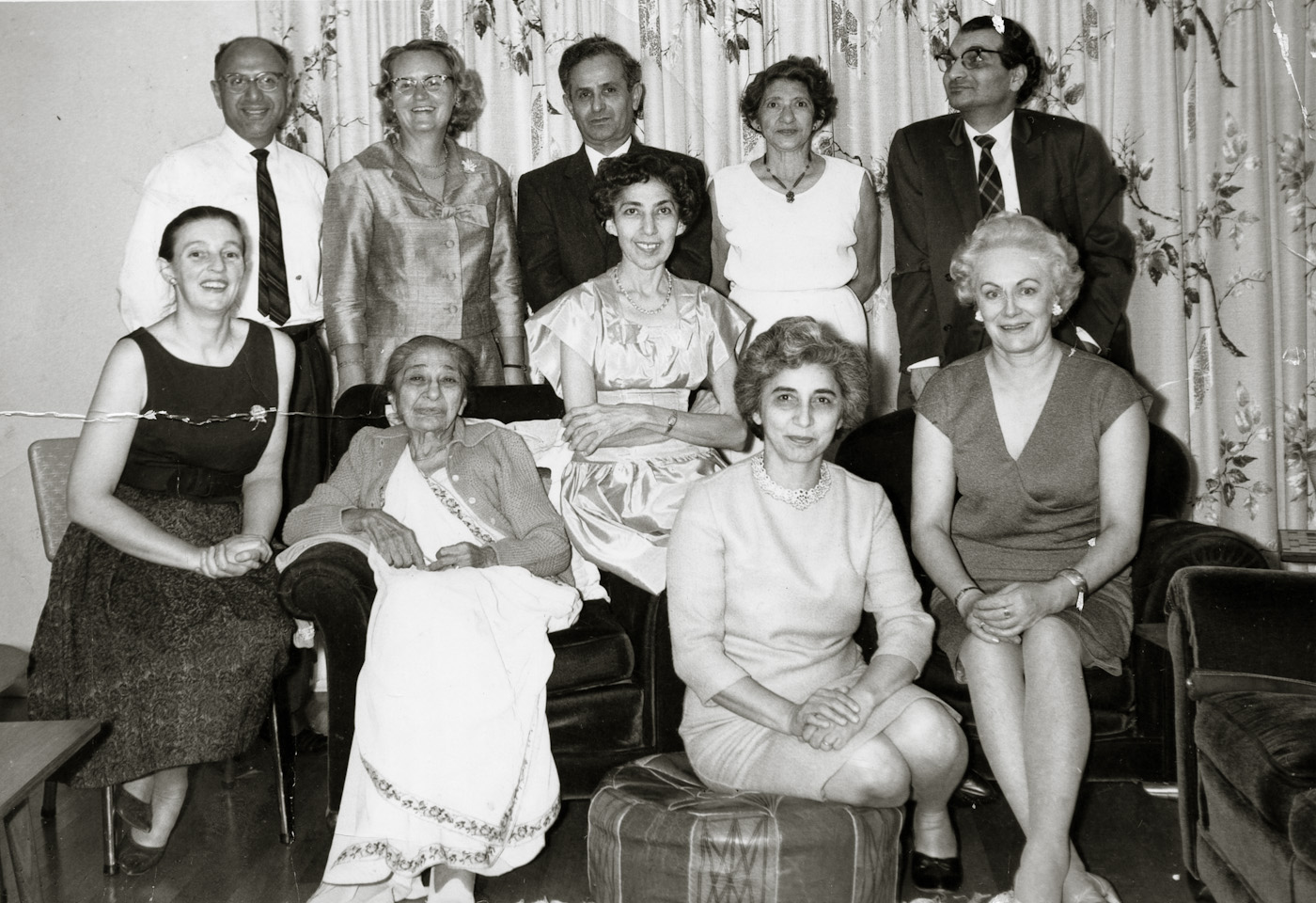 March, probably 1965. The entire Parsi community of the 1960s is in this photo.

Seated: (from left) My mother, old Mrs. Byram, one of her daughters (either Jilloo or Silloo - I cannot recall which), I cannot recall who the woman on the Ottoman was, possibly a third Byram sister?), and Mrs. Contractor.

Standing: Mr. and Mrs. Patel, Mr. Contractor, the other of the two Byram sisters, my father.

I knew the Patels for many years and Mrs. Patel (who is Dutch) attended the Unitarian church with my family. Aside from my mother, she is the only other person in the photo who is still alive. Mrs. Bryam was a sweet lady. I liked her very much. I recall, however, that she was diabetic and her daughters would slap her hand if she tried to take a candy or sweet. View full size.