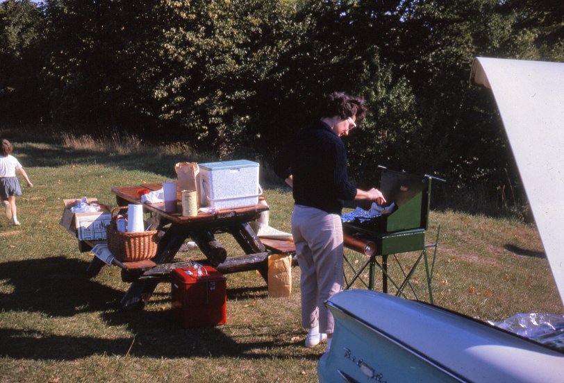 Here's the companion photo to the 1963 road trip to Canada last seen here at the roadside breakfast picnic table.  This time it's Mom's turn at the Coleman, but no note about which meal or where this was. Kodachrome slide. View full size.
