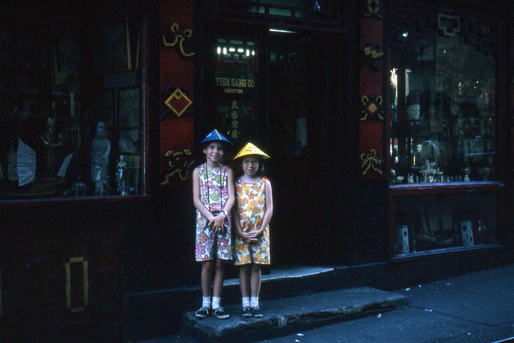 My sisters with their super cool Oriental hats.  Later, the yellow one flew out the window on the turnpike and its former owner could not understand why Dad couldn't turn around and pick it up.  Kodachrome slide. View full size.