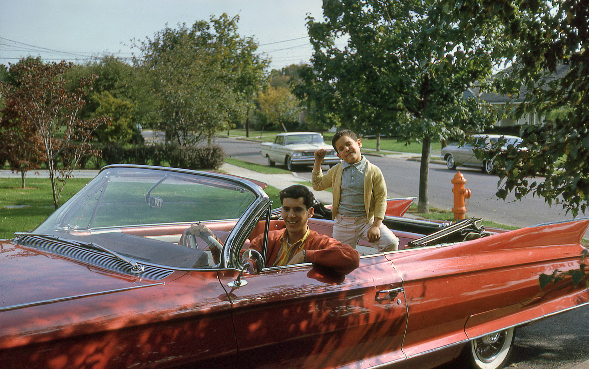 Big brother and little brother pose in Mom's new 1961 Cadillac. Seems big brother did a little damage. View full size.