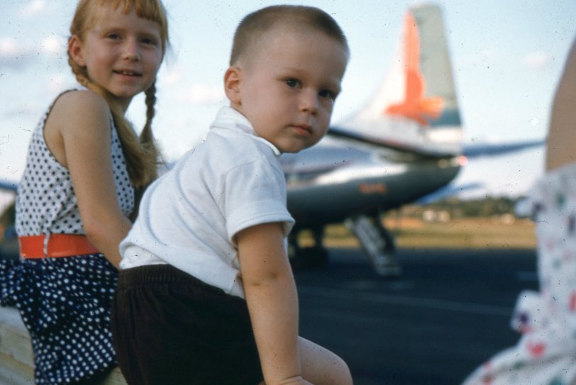 My mischievous, red-headed sister and I were sitting on the fence at the Greenville, South Carolina downtown airport in the summer of 1954.  In the background is an Eastern Airlines flight preparing for departure.  Ironically, the aircraft appears to be a Convair CV-240, the identical plane that would ultimately fly the band Lynard Skynard out of this same location for their final flight in 1977.  They ran out of fuel and crashed into a Mississippi swamp.
