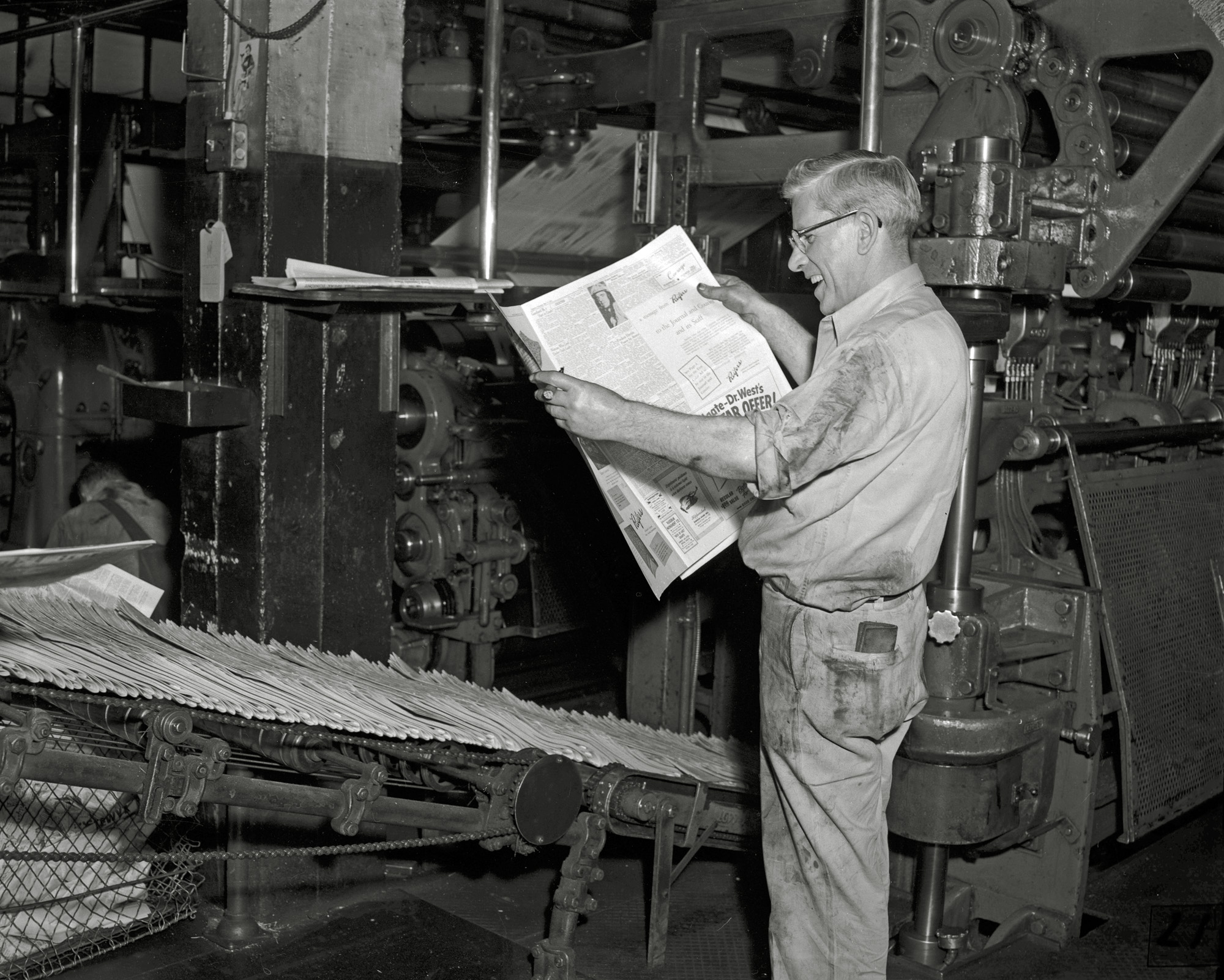 May, 1955. Lafayette, Indiana. The lead pressman at the Journal & Courier beams at the sight of the first ad to roll off of the updated press. View full size.