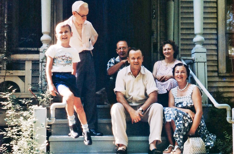 Niagara-on-the-Lake, Canada, Summer 1958. This is me, my Grandpa Peter, my parents, and Dad's cousin and wife. We were returning home from a road trip to Flint, Michigan, where other cousins of my Dad lived, back to Bedford, Quebec, where we lived at the time. 
My Dad's cousin owned the house in this picture, later to become Trisha Romance's (Canadian watercolour artist) restored Victorian home and gallery in Niagara-on-the-Lake. Grandpa Peter still operated his grocery store up King Street from here in 1958. I believe it was this same summer visit that Dad took that shot of me sitting on the steps in front of the store. View full size.
