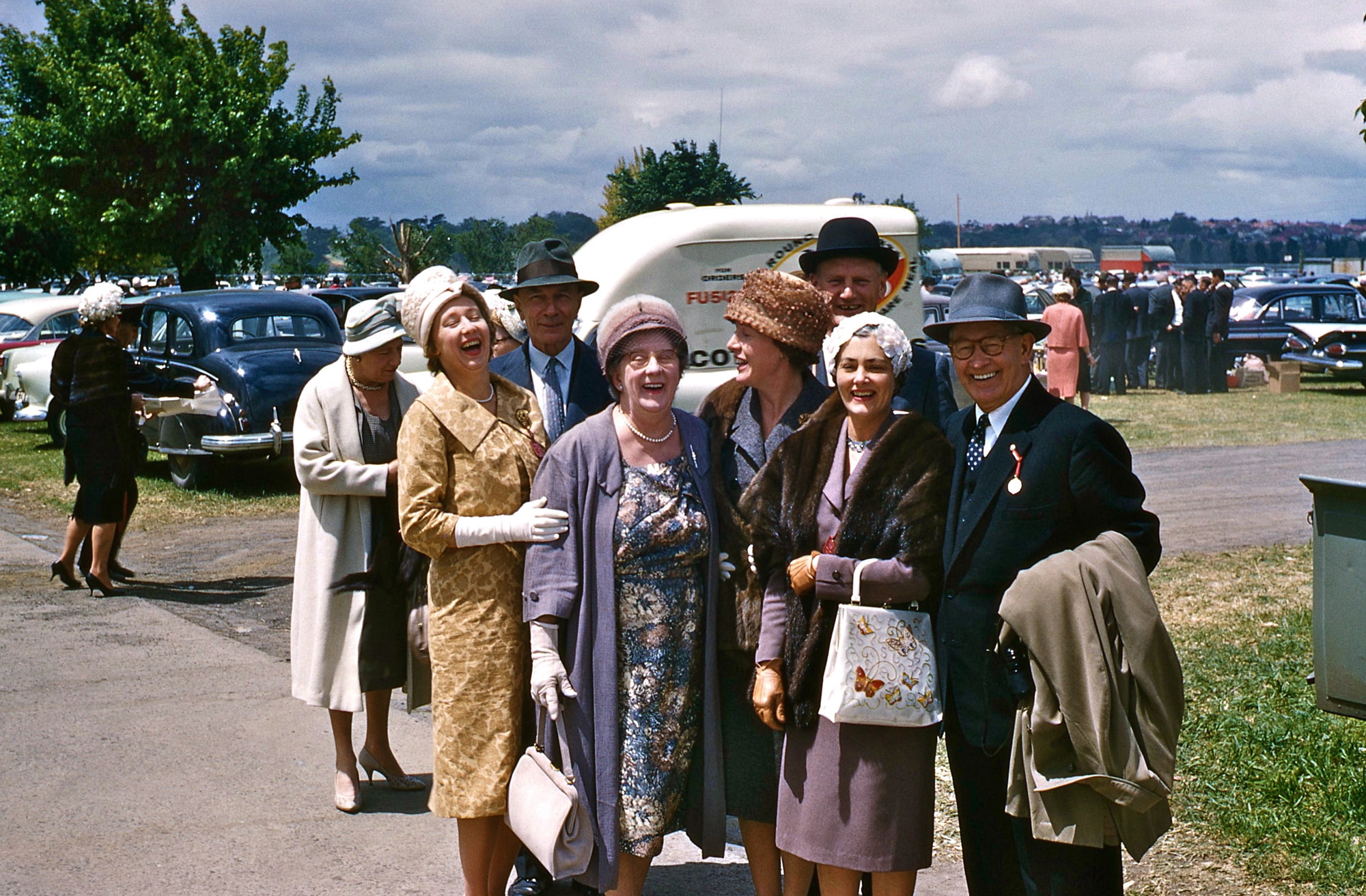 My father, John McIntyre, took this Kodachrome in 1959. It shows a group of Ford Motor Company of Australia staff and wives attending the Melbourne Cup at the Flemington Racecourse. Third from left is Charlie Smith, and my mother, Betty, is looking sideways in the brown hat. The man in the Homburg hat is "Norrie" Norris, and standing in front of him is his wife Trixie. What you see here is the Aussie version of a "tailgate party" prior to the races. It is still a dress-up affair to this day - click here for photos. View full size.