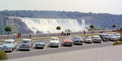 Shot taken using 35mm Kodachrome on the Canadian side of the Falls in 1958. Note the array of British and French cars among the American classics in the parking lot. Today, only tour buses are allowed in this area. The movie "Niagara," starring Marilyn Monroe, filmed the motel scenes (temporary props) off to the left of the picture at the gorge edge in 1954. View full size.
Kustom KarThe white Ford, fourth from the left, sports a '54 Pontiac grille, a common custom modification at the time. Spiffy.
SubjectiveIt's funny that in 1958 the photographer thought his subject was the falls. Now all these years later we know the subject is the cars!
Those European cars.In the parking line: a black Ford Pilot (?) third from the right.  Two to the left of it a grey Renault Dauphine with the roof rack and a suitcase.  Nice green Hilman Minx drophead third from the left.
The Minx was never a very sporty car, but in close proximity to the 'Yank Tanks' it looks positively rakish.
Prospect PointThis is the first photo I've seen that clearly shows the aftermath of the fall of Prospect Point, which occurred on Wednesday, July 28, 1954. It appears as a large, smooth, angled area at the left edge of the American Falls in this view. My parents and I were there five days before the collapse (as shown in this old color slide). That's Dad and me at the railing. The people in the background are standing in the area that fell, and I guess we are, too. Trouble was already brewing. When we took the elevator down to the bottom of the falls there were cracks in the concrete walls and water all over the floor. The next Saturday I went to the movies with my friends and the actual fall was in the newsreel. Quite a thrill for me, to think that I might have been standing there when it happened. Predictably, my buddies blamed me for the fall of Prospect Point, because according to them I was so "fat." ...HA!
Rare EdselOne of the first of the '58 model year (to the right of the Renault Dauphine).
The HillmanI'm amazed anyone else remembers the Hillman. That could almost be my brother's.  He bought it used in '65 and I think it spent more time in my folks' garage than it did on the road.  I remember using the crank start more often than not and that you could use a dime instead of a key to turn on the ignition.  It was such a wreck that he'd often borrow my old '57 Studebaker Scottsman for dates.
RecentlyThis is a photo, not street view, from Google Maps.
Poorly ParkedIt's interesting to see that poor parking is not just a modern phenomenon.  One person parks over the line and it affects half a dozen others.
From left to right it looks like we have:
1. Buick 1951 (Special?)
2. Chrysler 1953 New Yorker
3. Hillman circa 1953/54 Minx Convertible Coupe
4. Ford 1951 with a '54 Pontiac grille inset
5. Chevrolet 1957 Bel Air Convertible
6. Chevrolet 1953 210
7. Renault Dauphine 1956-58
8. Edsel 1958
9. Ford 1949-53 Prefect
10. Chevrolet 1957 210 Coupe
11. Ford 1952 Mainline Tudor or Business Coupe
Behind the last two cars are:
12. Likely a DeSoto 1957 (yellow)
13. Probably a Chevrolet 1955 (black)
The lady walking in the black dress along the wall behind the '57 Bel Air looks out of place with such a short dress on compared to the other woman in the photo.
Brown Is BrownThat '53 Chrysler New Yorker on the left sports the only brown auto paint I ever thought looked good.  My father had a '53 Imperial in that shade, and it was a dignified alternative to the normal conservative black yet far more stately than the washed-out pastel blues and greens prevalent on so many Cadillacs.
NiagaraThis isn't a tour bus only area now, they just charge you to park here.  The motel scenes in the movie "Niagara" were filmed in Queen Victoria Park which is to the right of this perspective.  To the immediate left is the Rainbow Bridge.  This is the area of the former Canadian terminus of the Honeymoon Bridge which collapsed in heavy ice conditions in January 1938.
HillmansHad a '57 Hillman Minx convertible back in '59; not super quick, but dashing in it's own way. Drove to Toronto and back from D.C.. 3 position top, snazzy. 
(ShorpyBlog, Member Gallery)
