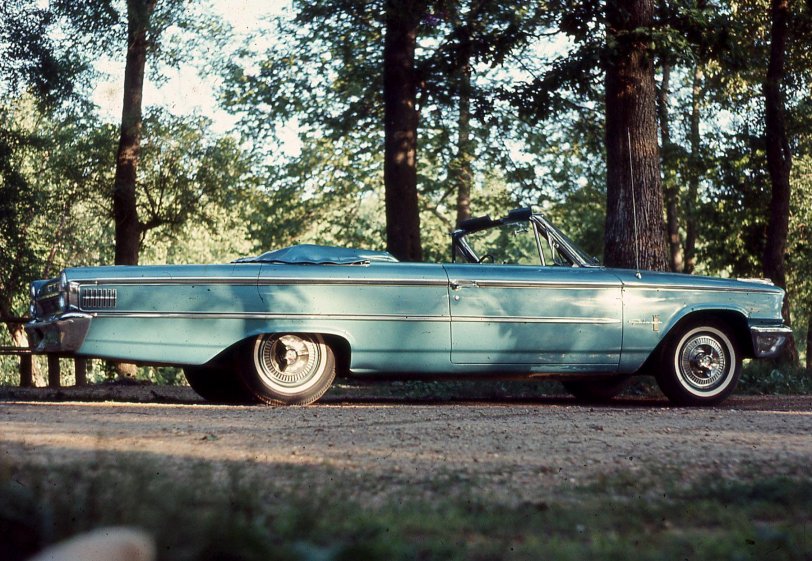 A 1963 Ford convertible. 3-speed manual transmission with electric overdrive, 352-cubic inch engine. The paint was metallic teal, which doesn't show up well in this Ektachrome slide I developed in my folks' kitchen sink. Did thousands of those. This was taken at Meramec State Park, near Sullivan, MO, I think. Almost as soon as I bought this car, I got drafted, so the guy I bought it from took it off my hands &amp; sold it again. He was a prince. This was in an age where, as they say, hearts were light and cars were heavy.
