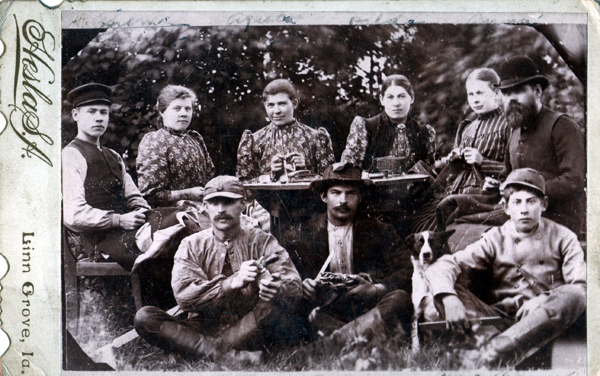 I came across this image so long ago that I can't remember where I purchased it. It has always been one of my favorites though for many reasons. First, I've always been taken with the expressions, especially on the men, even the dog!

Written on the reverse in ink is "Dads four sisters + brother Oscar and hirid (sic) help." Out of the four sisters, the only one who isn't looking directly at the photographer is the sister on the right sitting next to the stern looking man with the great derby hat. She's knitting, and she's the only one not wearing a dress made of the same material as the other three. I think it's possible that she may be blind or close to it. The other women are sewing, there is thread and some kind of sewing apparatus on the table in front of them). It seems that the fellow on the right in the derby and the young fellow in the hat on the left have some sort of pattern in their laps. Perhaps they are tailors. 

The three fellows seated on the ground have tools in their hands, but I can't figure out what they are exactly - except for the knife held by the one in the middle. Is it possible that the young fellow on the ground to the right is wearing some sort of Civil War uniform? I'm not sure when this photo was taken, but I get the feeling that it may be post Civil War. 

I also love the odd details of this image such as the torn hat of the man in the middle, the fact that the man in the derby is missing a button which and has used a pin to fasten his vest in its place, the way that the fellow on the ground to the left has only his top button fastened.
There are handwritten names above the women, but I can't make them out. Under the young fellow to the right is written "Unlce Oscar." The photgrapher's mark is "Hesla S.A." and the town's name "Linn Grove, Ia." (I found this online - www.linngroveiowa.org) is also printed on the image.