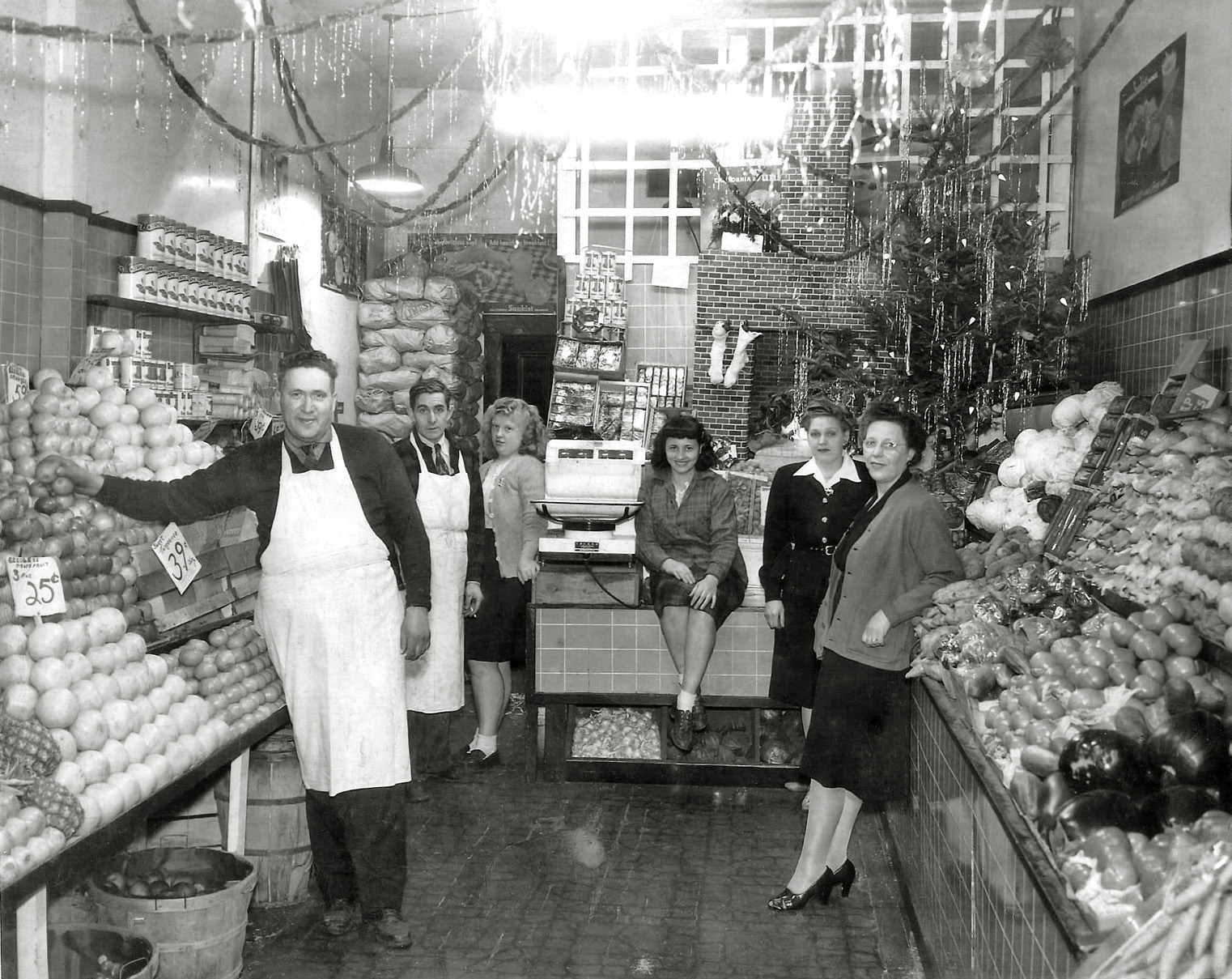 My mother, Lorraine "Rainey" LaFrance (nee Davis), center, at 17 worked at Irwin Produce Market on Main Street in Irwin, Pennsylvania.  She worked along with her father Russell, second from left, holding cigarette, and the owners, Sam Auchtenbaum, far left, and his wife Jenny on the far right. View full size.