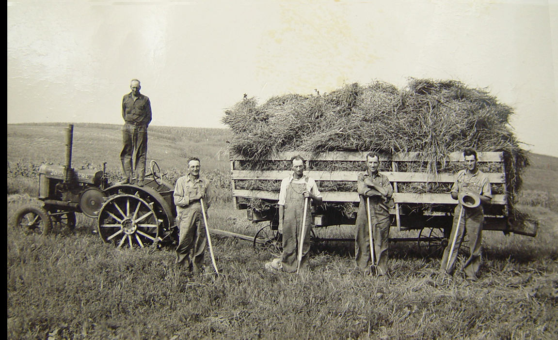 …and Young. My grandfather working (left with rake) at a neighbor's farm – I'm guessing the 1920s. He'd work his farm then also hire himself out to work others in the area as here.

The family homesteaded in Dakota Territory in the 1870s in what is now Union County in SE South Dakota a few miles from Akron Iowa. The homestead was on Bruele Creek, which is mentioned in, and the area is the setting, for the novel "Giants in the Earth" by Rølvaag. Most of the families in the area were Nordic and still reflected that when I'd visit as a child. 

Can anyone ID the year for the John Deere tractor to help place the time frame? View full size.
