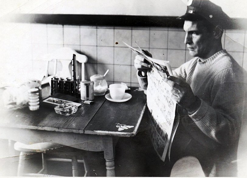 This is my stepfather, taken around 1960. He worked for the Newark Police Department, 4th precinct. I am curious, can anyone identify the object behind his ashtray? I know that a friend of his (maybe the one who took the photo) was a bus driver, that would account for the money changer on the table. I see a loaf of bread, sugar, a matchbook... View full size.
