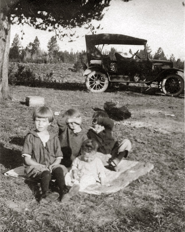 My grandmother up front left in this picture along with her siblings, taking a break on their journey to Yellowstone from Burley Idaho, around 1920. Imagine making the journey on the roads back then in those old cars back then.  View full size.
