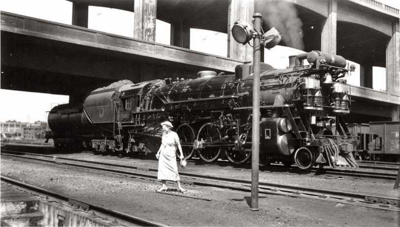 Most locomotive portrait artists were consummate professionals who didn't allow things like light poles--or old ladies--to obscure their subject.  Whoever took this photo wasn't on his game apparently.  The old lady--a rather comical figure, is she not?--is probably the photographers wife, but I like to think she's lost and wandering around the Cincinnati Union Terminal service area looking for the ticket window.  The locomotive, for those who care, is C&amp;O Pacific type #492.  Photo dated July, 1937.  View full size.
