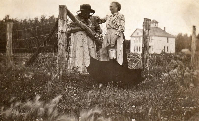 My grandmother Elizabeth Fitzpatrick (left) laughing over the town commons fence with her mother-in-law, Great Grandma Margaret Fitzpatrick in St. Vincent, Minnesota.  Town school in the background.  Circa 1925. View full size.
