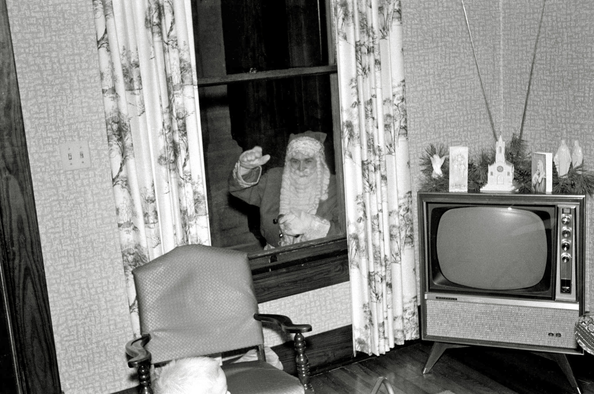 This picture is from the early 1960s.  Every year my mother's family gathered at the farm house to celebrate Christmas Eve.  For a brief few years Santa arrived during our party to distribute gifts.  I was young enough and excited enough not to notice the absence of my Uncle Tommy during Santa's visit.  As Tommy's boys became old enough to be aware of his absence, Santa stopped coming to the party.

Uncle Tommy was reasonably serious and reserved healthcare professional, so it is fun to see him hamming it up, giving us all a thrill for Christmas. View full size.