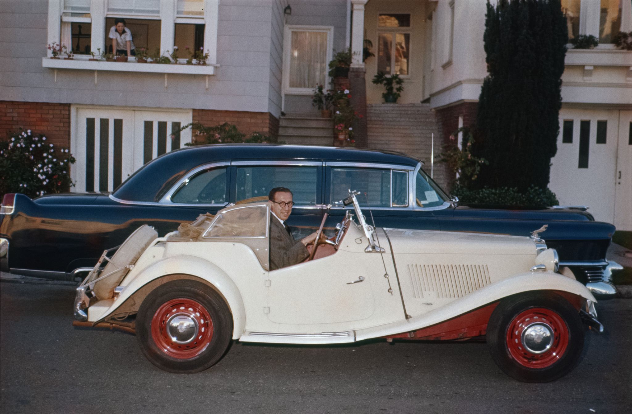 Someone took this Ektachrome slide of my uncle in his newly-acquired MG around 1955, in front of his San Francisco home (on the right). Why the Caddy limo is there, or if it's connected with the event, I don't know; based on the front fender trim, I think it's a '54. Appears to be a registration certificate taped inside the windshield.  I presume it's parked facing the wrong way on the street because Cadillac limos get to do that. Next-door neighbor kid seems entranced by the scene, as I would have been. View full size.