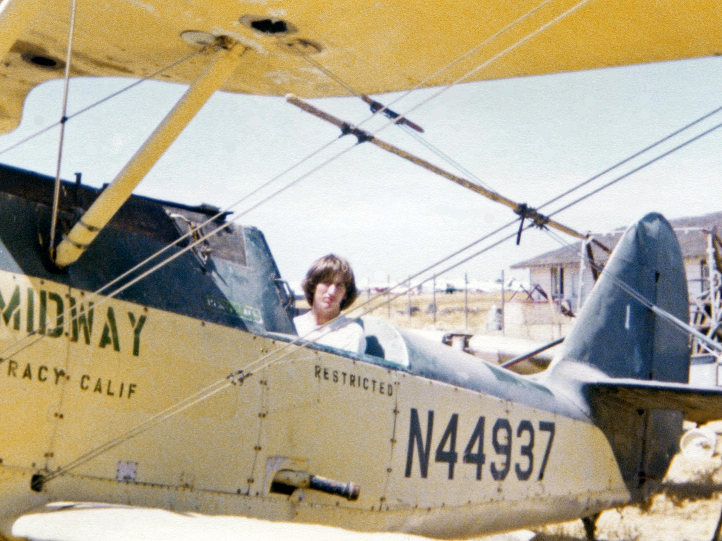 There I am at the August 1979 Madera, California "Gathering of Warbirds" airshow and I am sitting in a derelict WWII-era Naval Aircraft Factory N3N Navy flight training biplane. It had been sold surplus after its military service and converted into a crop duster and no doubt saw heavy use before it was retired, parted-out, and pushed into the weeds. I just had to climb in and my friend took the picture. View full size.