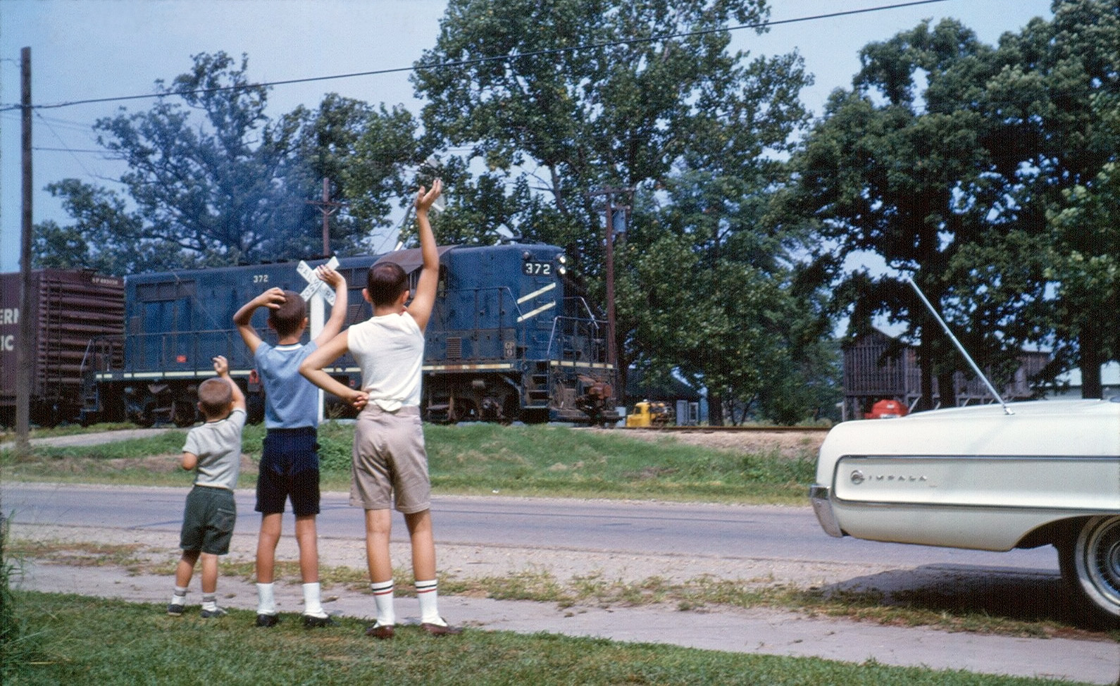 My two younger brothers and myself waving at the train which passed by twice a day on the track across the road from our grandparent's home. Morehouse, Missouri, 1967.  Kodachrome slide. Any advice on optimal methods to scan slides would be appreciated! View full size.