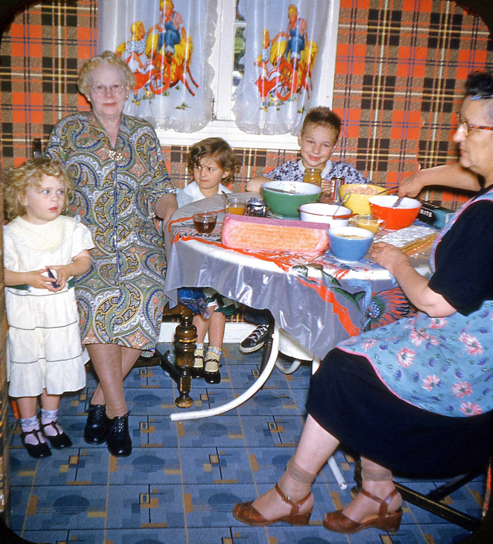 A mad clash of colors and styles in this vintage Kodachrome; I love it all, but not all in the same room. It's one side of a mounted 3-D pair from a collection found in a thrift store. I'm fairly certain the woman making the cake is the mother of the young boy behind the table, but I'm not sure of the others. View full size.