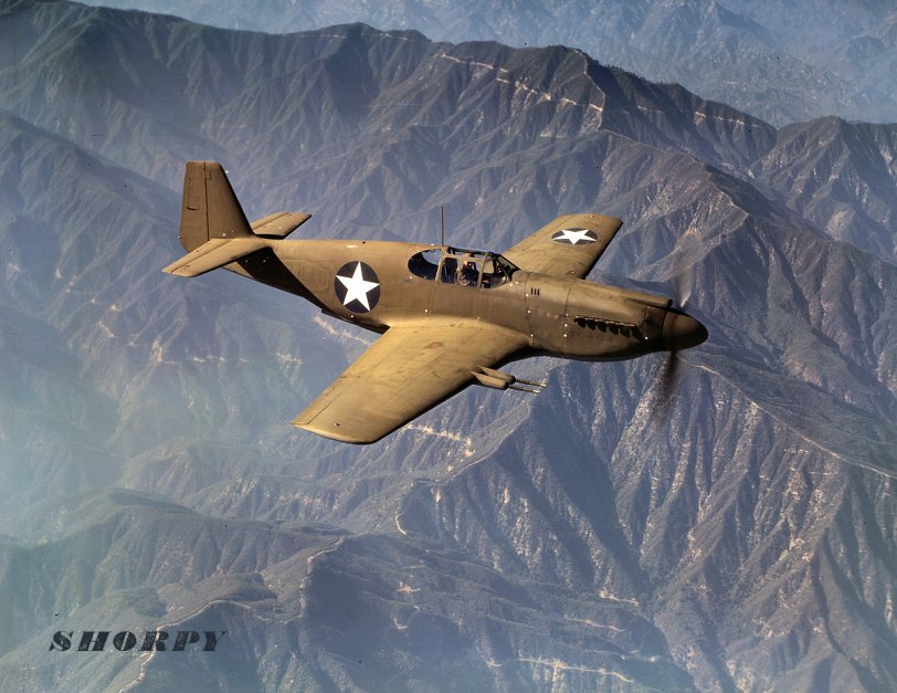 October 1942. P-51 "Mustang" fighter in flight near the Inglewood, California, plant of North American Aviation.  4x5 Kodachrome transparency by Alfred Palmer. View full size.
