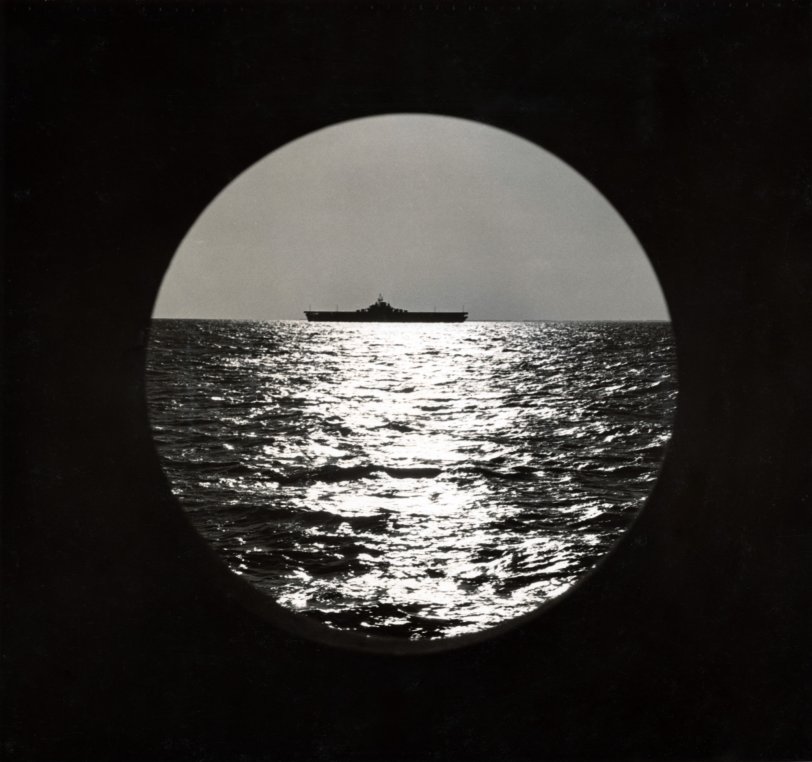 In this image, the USS Franklin can be seen from aboard the USS Duane. According to a site dedicated to the USS Franklin, the ship spent a majority of its time in World War II in the Pacific. The ship has an unbelievable history of its own – it was the closest US carrier to the Japanese mainland, and was attacked by a Japanese plane. During the attack, 724 crew members were killed and 265 were wounded. Amazingly, the battle torn ship did not sink and eventually made its way back to New York. It has been called “The ship that wouldn’t die”.
This photograph came from my grandfather John "Jack" Baker's Warbook. This book contains pictures from while he was in the USCG on the cutter ship USS Duane. This image is believed to have been taken from it. 
In looking at the USS Franklin’s history – it was on the East Coast of the United States and sailed to Trinidad in March of 1944. It is likely that this photograph was taken during this time as it was in the Pacific thereafter – while the USS Duane was in Europe. The photographer of this image is unknown as Dale Rooks (who took many of the other photographs in the Warbook) wasn’t on the ship during the time period this was believed to be taken. View full size.
