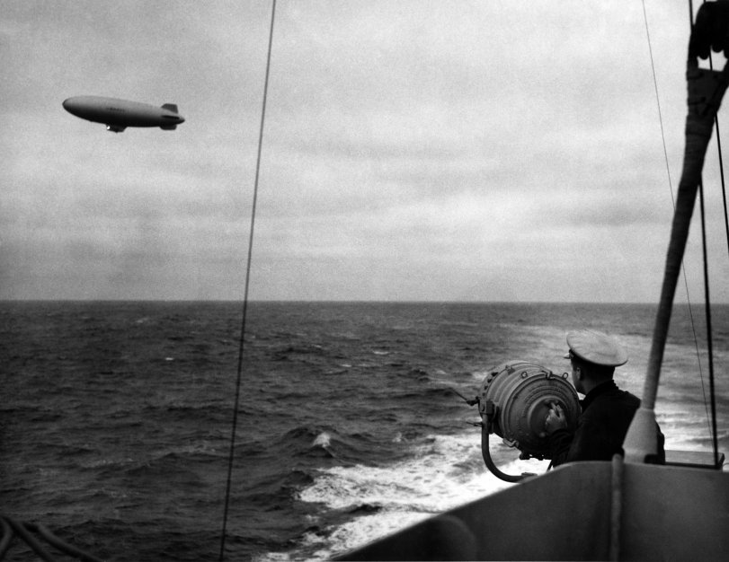 This image was scanned from my grandfather John "Jack" Baker's Warbook - which contains over 150 original images from his time in the US Coast Guard during WWII.
In this photo, we have a US Navy blimp signaling the USCG cutter USS Duane. If you look closely at the blimp, you can see that it has a signaling light turned on. Unfortunately, the location date and photographer are completely unknown. This photograph was among others that were labeled 1943 North Atlantic, so that would be our best assumption as to the date and location.
After doing some research, I believe this is what is called a “K Class” blimp. In looking at Navy Squadrons that flew during World War II, it is likely that this was part of the ZP-12 which hunted German U-Boats in the North Atlantic. Another possibility is that this was part of the ZP-14 squad, which sailed in North Africa. If anyone has any information about joint Navy and Coast Guard convoys during WWII, I would be very interested in hearing about them. View full size.
