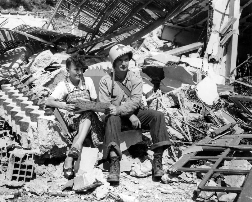In this photograph my grandfather John “Jack” Baker can be seen getting directions from a French Woman. They are seated on the ruins of a building in Southern France after it was destroyed by German forces. This image was likely taken around or on August 16, 1944. Although there is no way of knowing the exact location, the USS Duane was docked near Baie de Cavalaire as it took part in “Operation Dragoon”. This photograph was definitely taken by Dale Rooks, as the back of the image was stamped with his name. This image comes from my grandfather's "Warbook". View full size.
