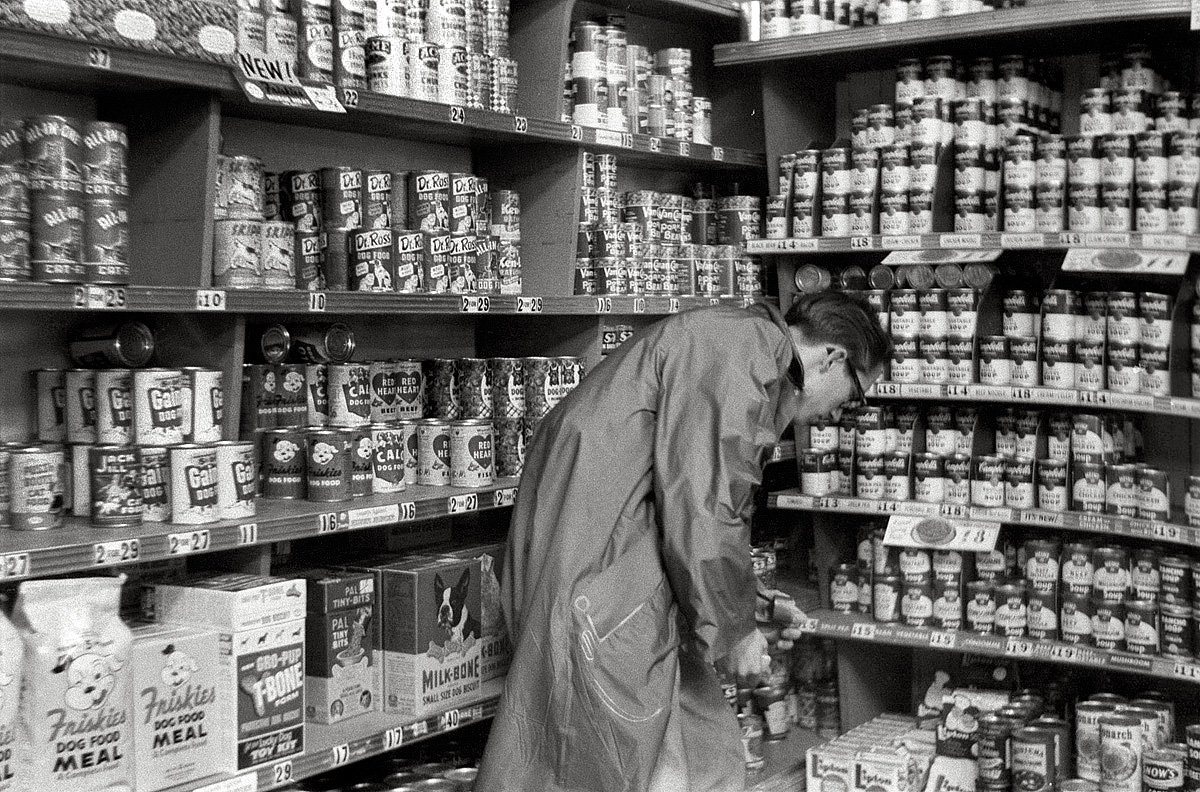 April 21, 1955. Using the self-timer on his new Lordox 35mm camera and a roll of high-speed Kodak Tri-X film, my brother photographed himself in what appears to be the canned soup and dog food section of the Rainbow Market, the exterior of which can be seen here. View full size.