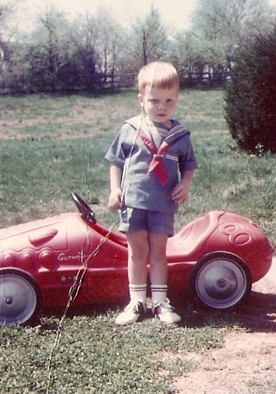 Here we have #8, the Red Racer.  This is in Louisville about 1963 or so.  At some point after this was taken, my dad and I went flying down the driveway of our apartment building.  However, we neglected to notice the freshly paved asphalt until it was too late, and we trashed Red Racer and ourselves in the process!  I recall my grandfather "J" drilled a hole in the back so he could push Red Racer with a stick.  My last name's hand-painted on the side just like the Indy drivers!  I think there were wooden blocks attached to the pedals so I could reach 'em, too.