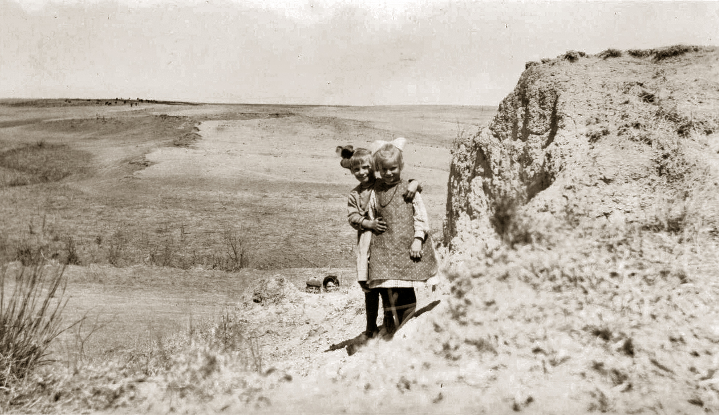 My grandmother Dottie and a schoolmate photgraphed by the teacher of a one-room schoolhouse in the early 1920s in rural SW Nebraska. Note the two "spies" peeking from behind the ridge in the center of the photo. View full size.