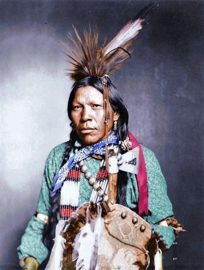 A colorized version of a photo of an Indian in native dress titled "Runs Medicine," c. 1899. View full size.
