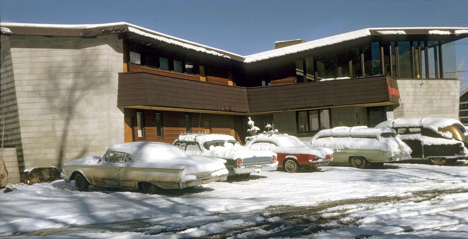 Aspen, winter 1962-63. Boomerang Lodge, designed by owner Charlie Paterson, a Frank Lloyd Wright-trained architect. The vehicle on the right is a Cadillac hearse used as a lodge limo! My 1960 Ford convertible is on the left. View full size.