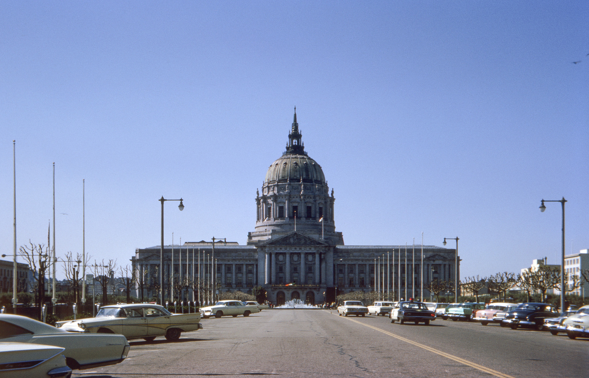 San Francisco City Hall on March 14, 1965. I was with friends to take in the St. Patrick's Day Parade and we apparently tooled around beforehand, giving me an opportunity to take this Kodachrome slide with its smattering of cars, some of them already classics. Back in 1956, Chryslers of that year with their big, luscious tail lights had been among my favorites, and here we have two of them. Among the others, an old bathtub Lincoln, a later-model Thunderbird and a smidgen of a Corvair. If you want to park here now, forget it. Later on at the parade, I took this shot featuring another car, and also a governor. View full size.