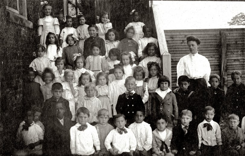 One of my favorite images from my collection. I'm guessing it to have been taken between 1890 and 1910 based upon the style of clothing. I'm assuming that this is a class photo taken right outside of the school. 
All I know is that it was more than likely taken somewhere in New Jersey. One of the children (the girl with the somewhat severe haircut in the gray overcoat with the white collar to the lower left of the teacher) appears in other photos in the collection I was given with an older boy, most likely her brother. Oddly enough, the photos of her seem to stop at around the age of 10 or so, where photos of the boy take him into adulthood. Perhaps she died at an early age.
I find it fascinating that a classroom from over 100 years ago is so racially diverse. More likely than not, the majority of these children are from immigrant parents from around the globe and may themselves be first generation born in this country. I find this photo rather historic on that level.
