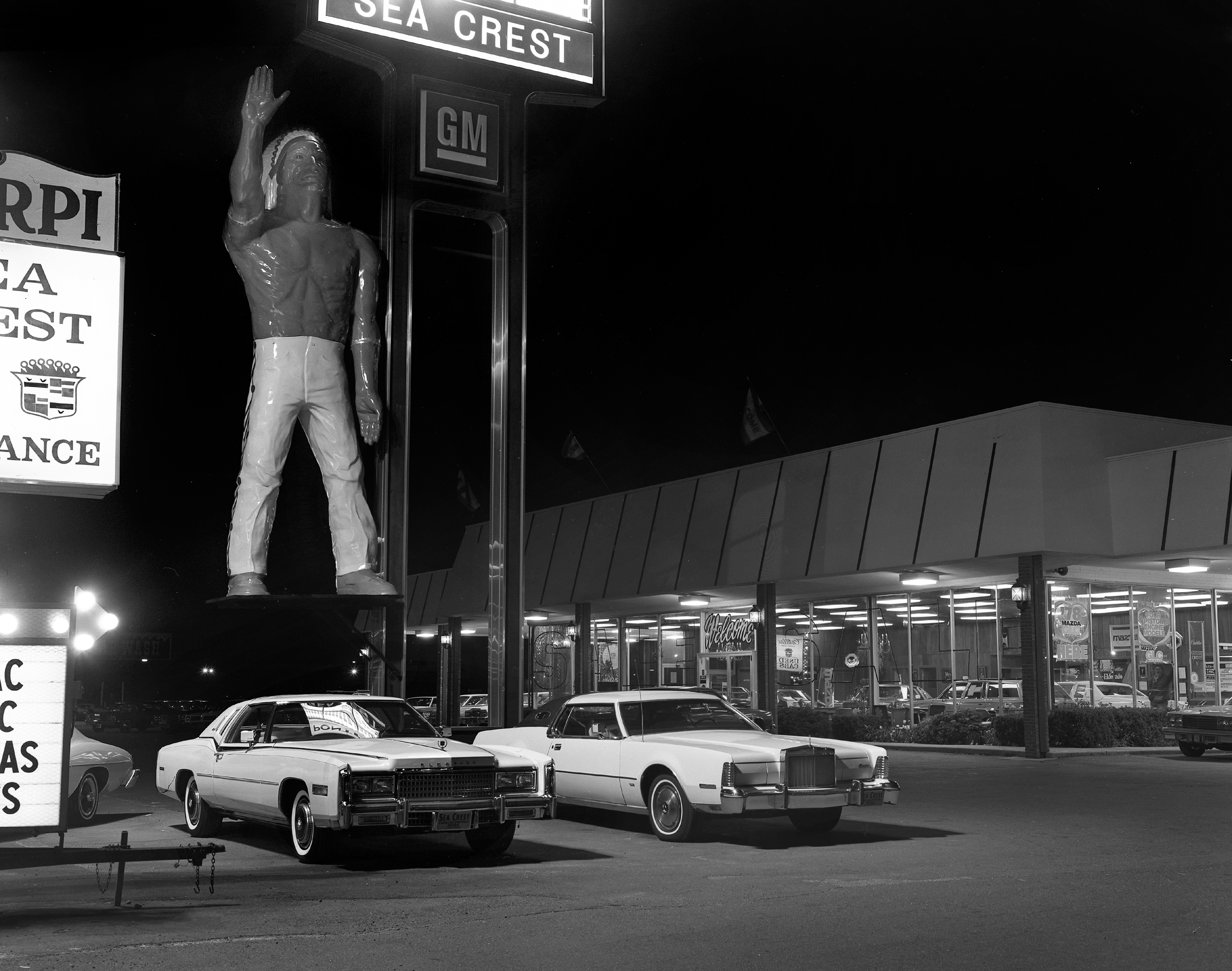 Fall 1977. Sea Crest Motors was a Cadillac-Pontiac-Mazda dealership on Route 1A in Lynn, Massachusetts. The Indian could be a reference to Pontiac, the Native American chief and namesake for the car company. Very impressive to gaze up to at night; I don't think he sold many cars though.  View full size.