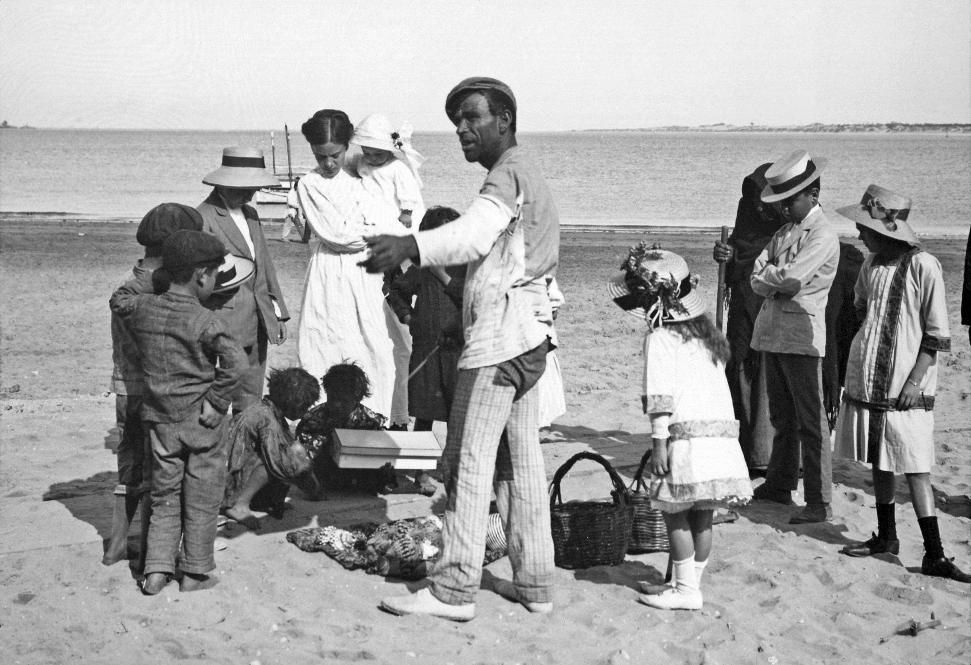 Selling seashells at the beach in Sanlucar de Barrameda, Spain, c.1915. Positive in glass taken by my great-grandmother's brother. See the huge class differences existing amongst the two or even three groups of children in picture, but all of them are curious about the same things. We all are equals no matter what kind of dress you wear. It is true now and it was true then. View full size.