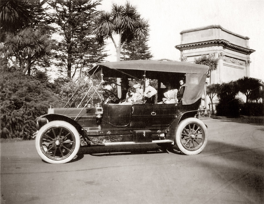 This looks like it was taken in San Francisco. The lady in the front seat looks like she is holding a doll. Car appears to be from mid teens.