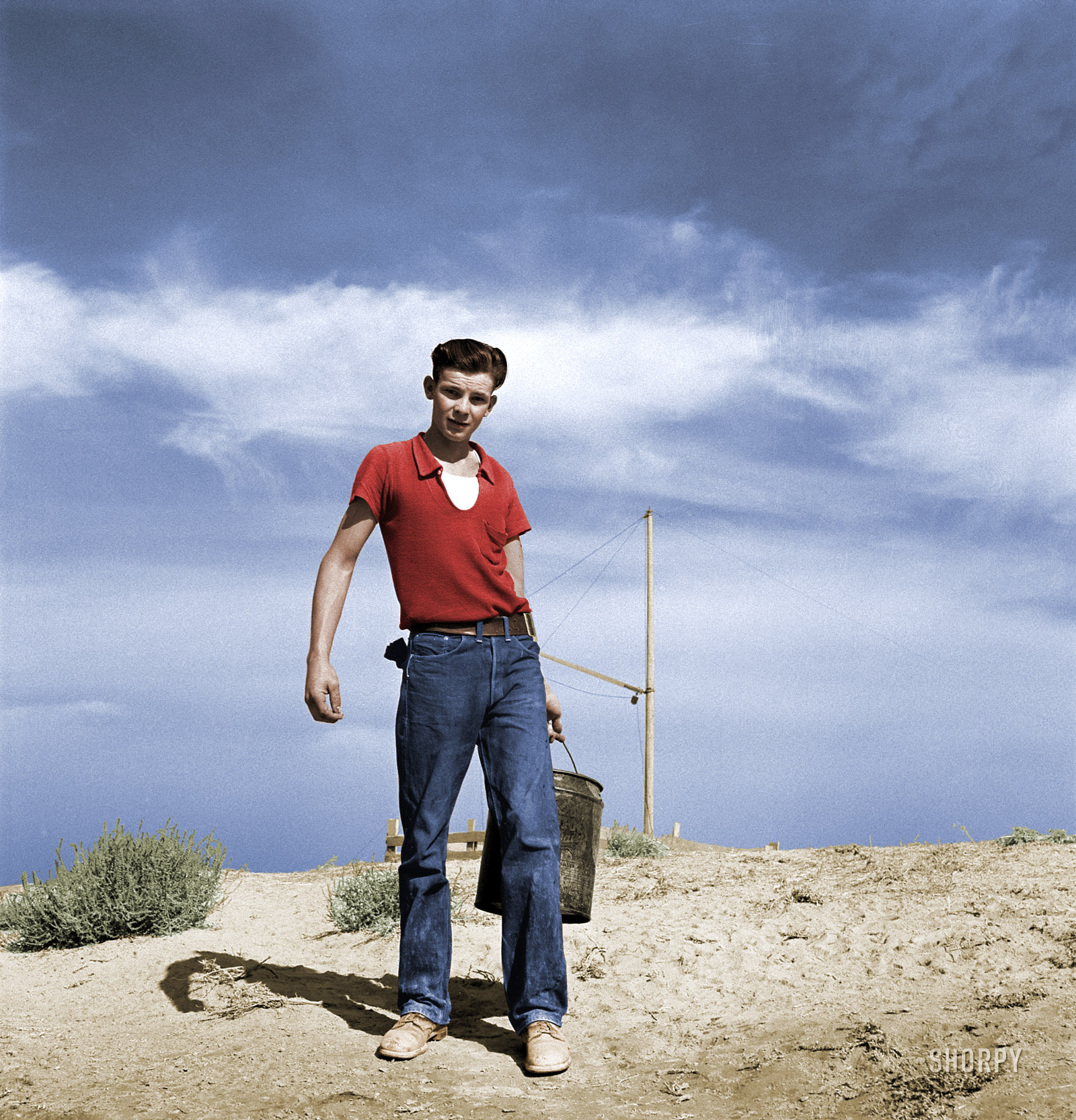 Colorized from this Shorpy original. A young man is carrying a bucket in an arid agricultural setting.  However, there is no crop, the bucket appears to be empty, and he does not appear to be dressed for work.  He looks ambitious and well-prepared, and he probably did well in life. View full size.